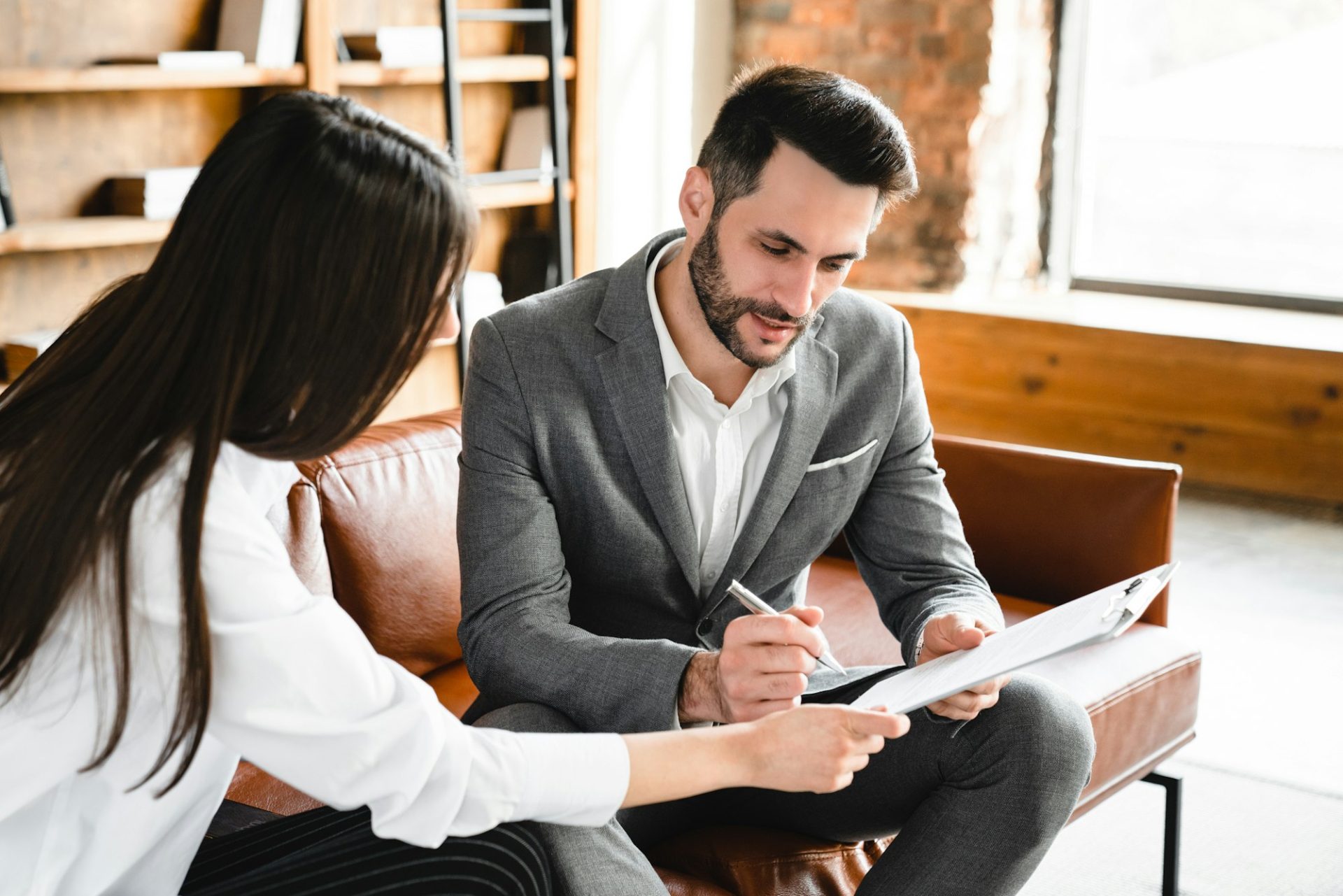 male and female business colleagues signing legal documents together in modern office